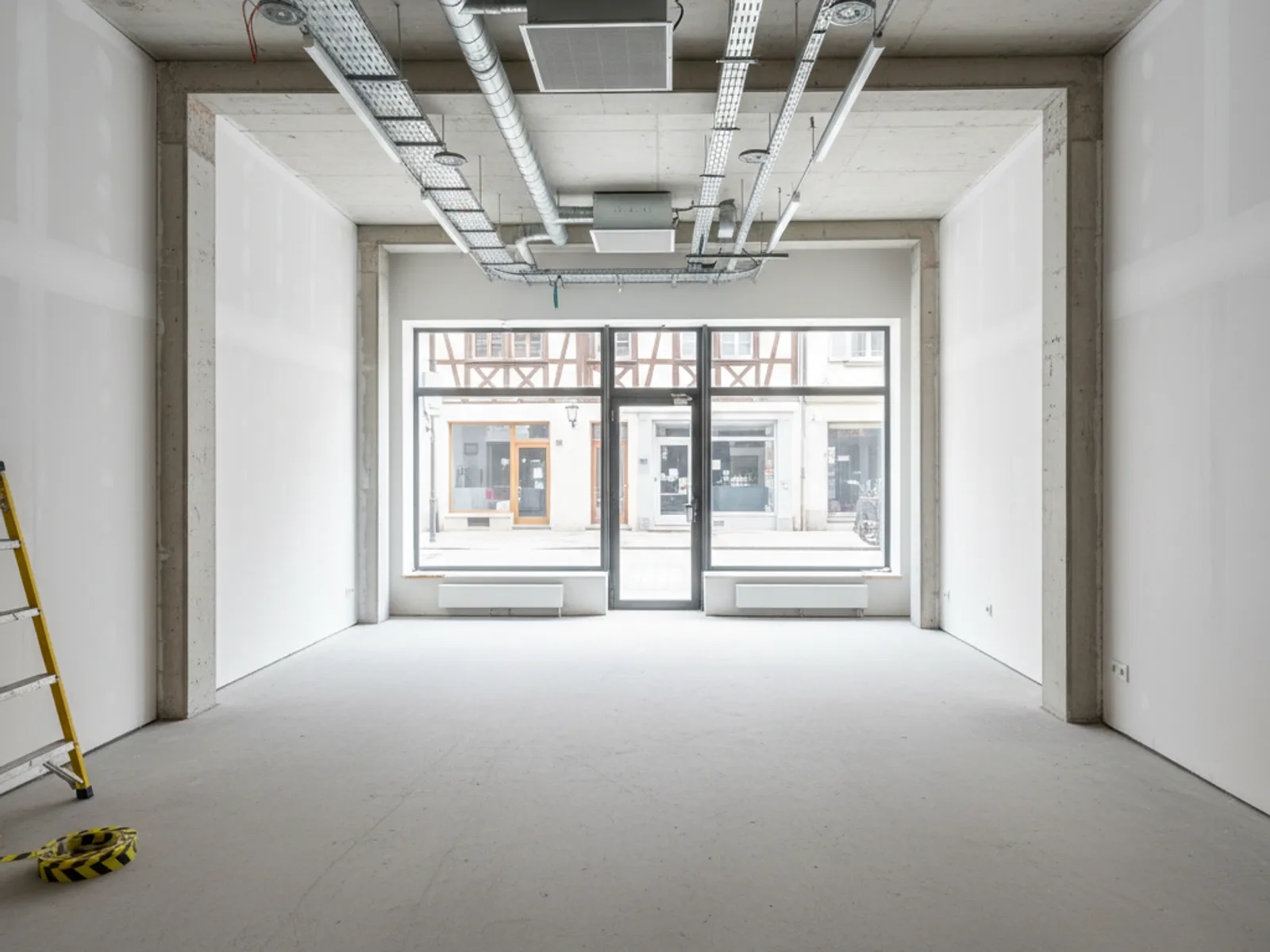 Local commercial remis à blanc avec vitrine neutre et sol béton